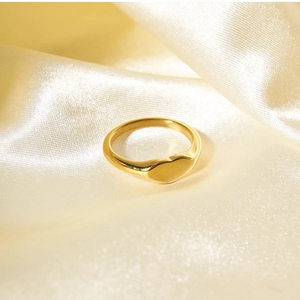Close-up of 18K gold plated heart ring on elegant champagne silk fabric background