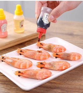 Detailed shot of hands squeezing a mini portable sauce bottle over cooked shrimp
