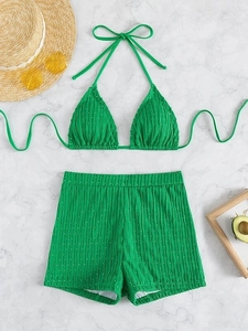Flat lay of green ribbed bikini with high waisted shorts and summer vacation accessories