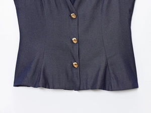 Vue détaillée du gilet en lin bleu foncé avec trois boutons ronds en métal doré