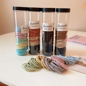 Multi-colored knitted hair ties set in clear storage tubes with handmade aesthetic style
