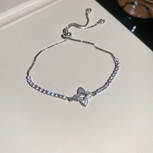 Macro view of adjustable silver bracelet with zircon flower charm and tennis chain detail