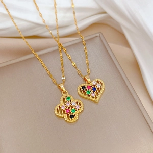Detail view of gold clover and heart pendants with colorful crystals on titanium steel chains