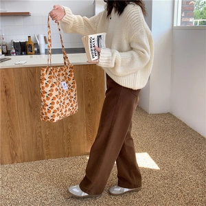 Detalle del bolso tote de pana naranja floral combinado con jersey blanco de punto