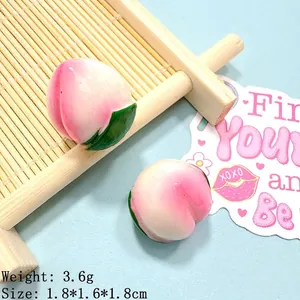 Detail shot of a 1.8cm resin peach charm with pink gradient and green leaf for DIY crafts