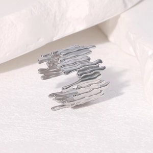Bague minimaliste en acier inoxydable style lave liquide sur fond de pierre blanche