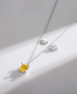 Macro detail of S925 silver necklace with yellow square gemstone and Leo zodiac charms