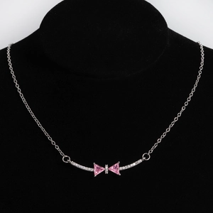 Detail of silver bow necklace featuring pink triangular gemstones on a black bust stand