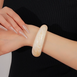 Detail of minimalist cream marble resin wide bangle worn on wrist showing texture