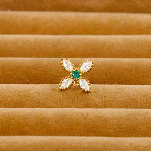 Macro shot of gold floral cartilage stud with green zircon and clear marquise stones