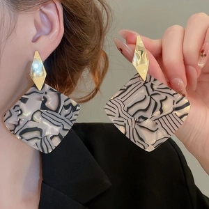 Detailed view of oversized geometric diamond earrings with black and white marble pattern
