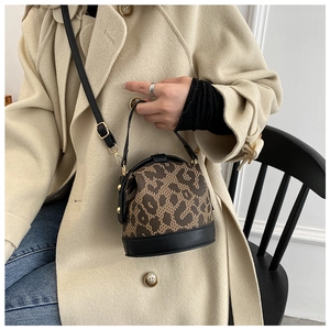 Detail of leopard print bucket bag featuring black leather handles and gold metal accents