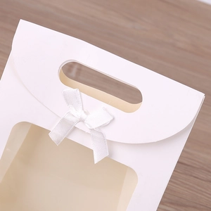 Close-up of white gift bag with transparent window and elegant ribbon bow detail