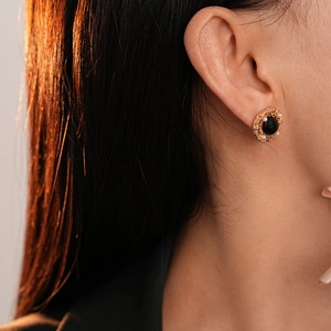 Gros plan détaillé d'une boucle d'oreille vintage dorée avec pierre noire et perles
