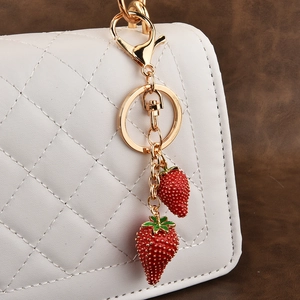 Fashion strawberry fruit keychain with red charms on a white quilted handbag detail