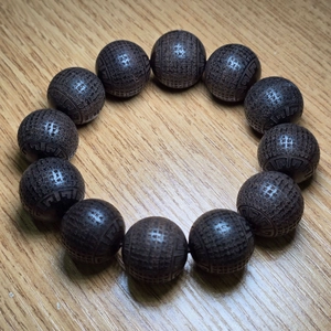 Détail de perles de prière en bois d'agar brun foncé avec écritures chinoises gravées