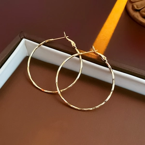 Macro shot of gold hammered round hoop earrings with leverback closure in a jewelry box