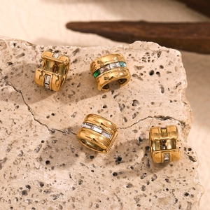 Close-up of gold-plated ear cuffs with emerald, blue, and yellow rectangular gemstones