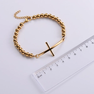 Detailed view of a gold beaded cross bracelet with a ruler showing the 4.5cm pendant size
