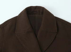 Detail of lapel collar and shoulder stitching on dark brown wool coat with premium texture