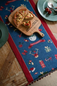 Detail of blue Christmas table runner with snowman patterns and red tassel edges