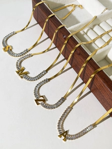 Detail of 18K gold plated snake bone chain necklaces with zircon and initial pendants