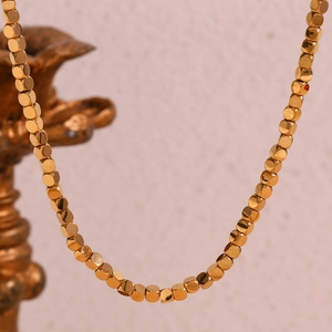 Detailed macro view of 18K gold plated stainless steel cube beads on a modern chain