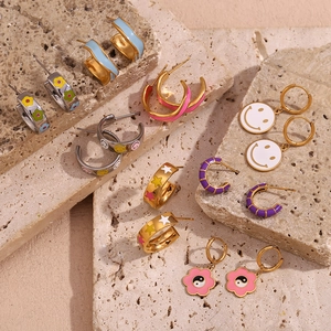Close-up of 18K gold plated hoop earrings with colorful enamel charms on stone