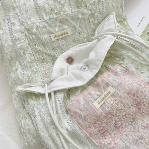 Close-up of light green velvet bag with floral embroidery and silver magnetic buckles