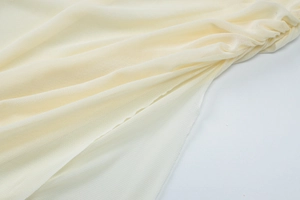 Detail of sheer mesh fabric with soft pleats on a light yellow sleeveless dress