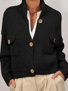 Detailed macro shot of textured chunky knit fabric and large wooden buttons on black cardigan