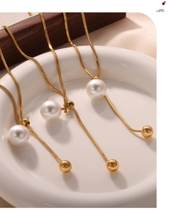 Detailaufnahme goldener Schlangenketten mit weißen Perlen und polierten Metallperlen