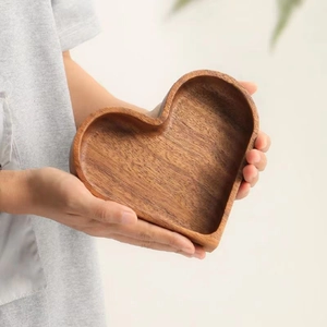Close-up of hands holding a heart-shaped walnut wood tray with natural grain finish