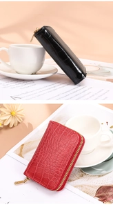 Detail of crocodile pattern leather card wallets in black and red with gold zippers