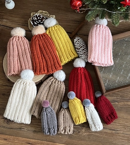 Detailed view of colorful knitted mini Christmas hats with pom-poms on a wooden table