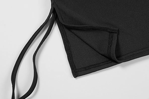 Detail of black rib-knit fabric featuring side slit and double drawstrings on dress
