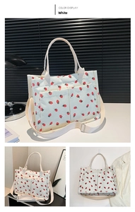Detail view of white corduroy tote bag with strawberry print and adjustable shoulder strap