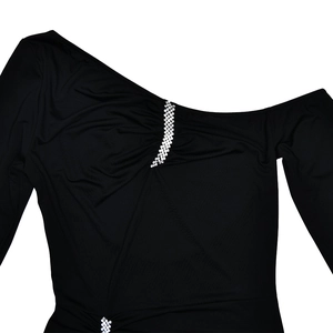 Detail of one-shoulder black dress featuring rhinestone chains and pleated fabric texture
