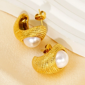Détail macro de boucles d'oreilles tressées en C plaquées or avec perles blanches