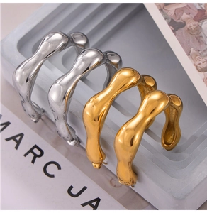 Macro shot of irregular molten-style C-shaped hoop earrings in gold and silver finish