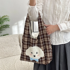 Detail of cute plush dog embroidery and blue bow on brown plaid fabric tote bag