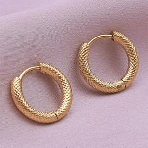 Detail of gold hoop earrings with textured snake skin pattern on purple fabric