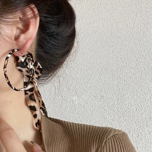Close-up of leopard print chiffon bow earrings on model showing fine fabric detail