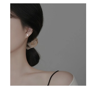 Macro detail of a 925 sterling silver heart-shaped stud earring worn on a model's ear