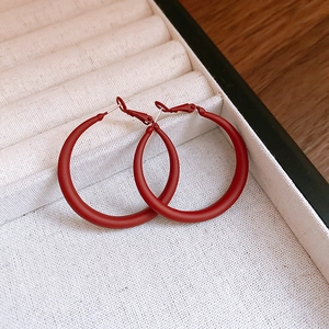 Close-up of red matte metal C-shaped hoop earrings inside a jewelry box storage