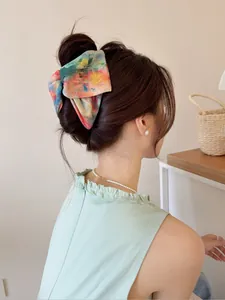 Détail d'un grand nœud papillon tie-dye porté sur une coiffure relevée élégante