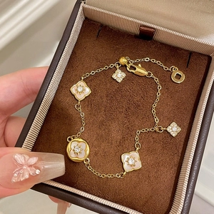 Elegante bracciale in oro con motivi a stella in zircone e ciondoli a quadrifoglio