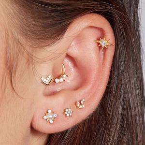 Close-up of gold S925 silver ear studs featuring pearls, zircon stars, and opal moon