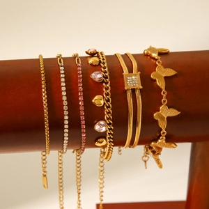 Detailed display of assorted gold bracelets with crystals and butterfly charms on wooden stand
