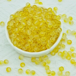 Macro shot of 6mm bright yellow frosted glass beads in a white bowl for DIY jewelry